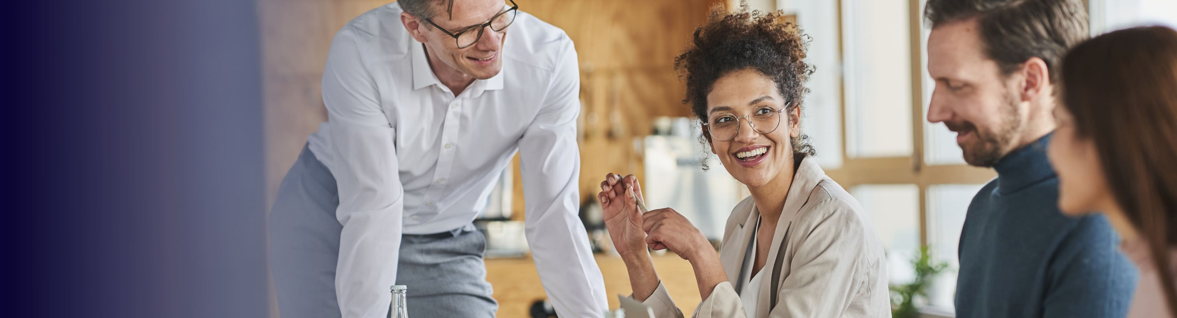 Four people in a professional setting engaged in a discussion or meeting. Faces are blurred for privacy, suggesting a collaborative work environment.
